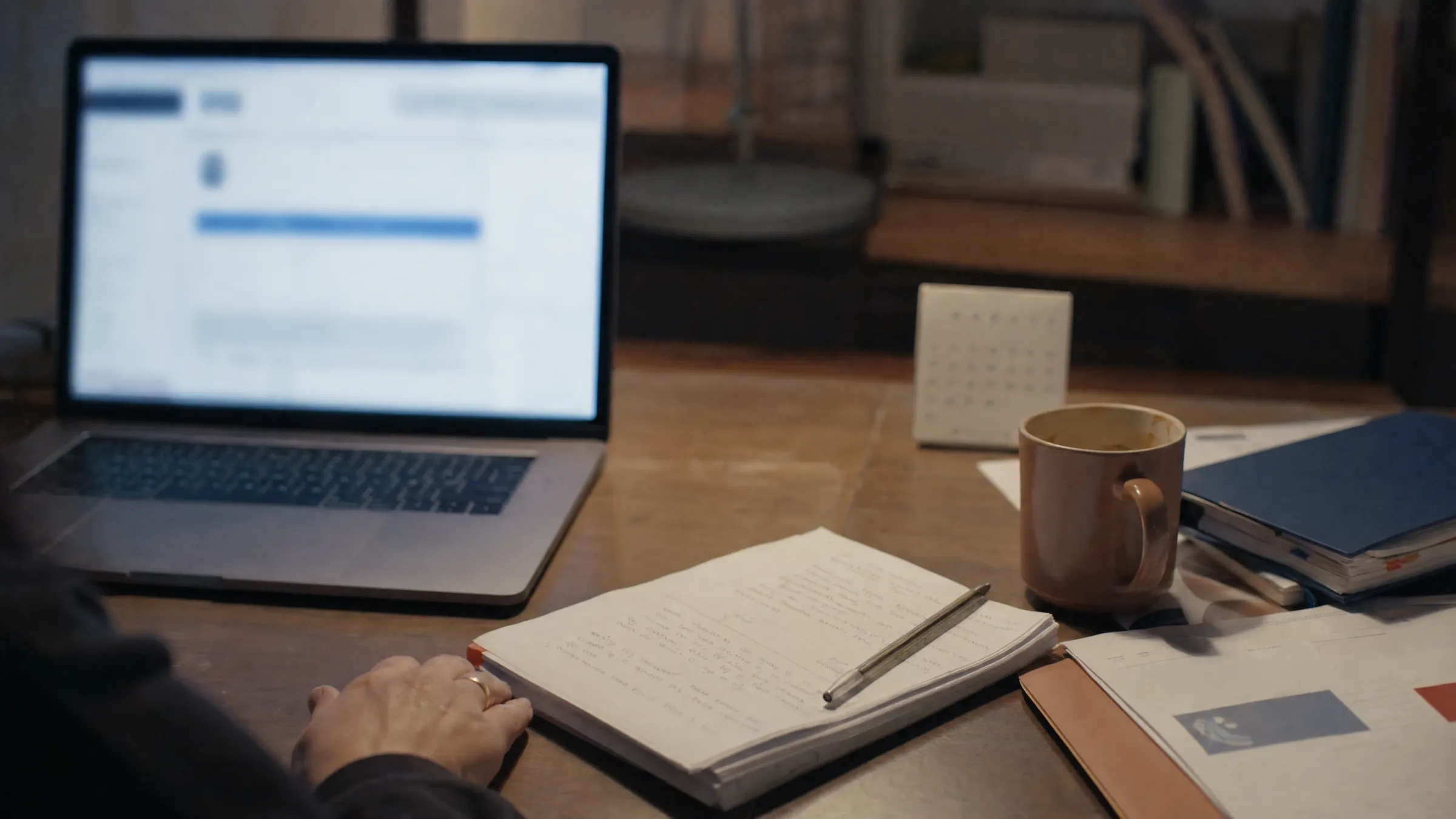 Bureau familial avec ordinateur, carnet et portail administratif anonymisé.